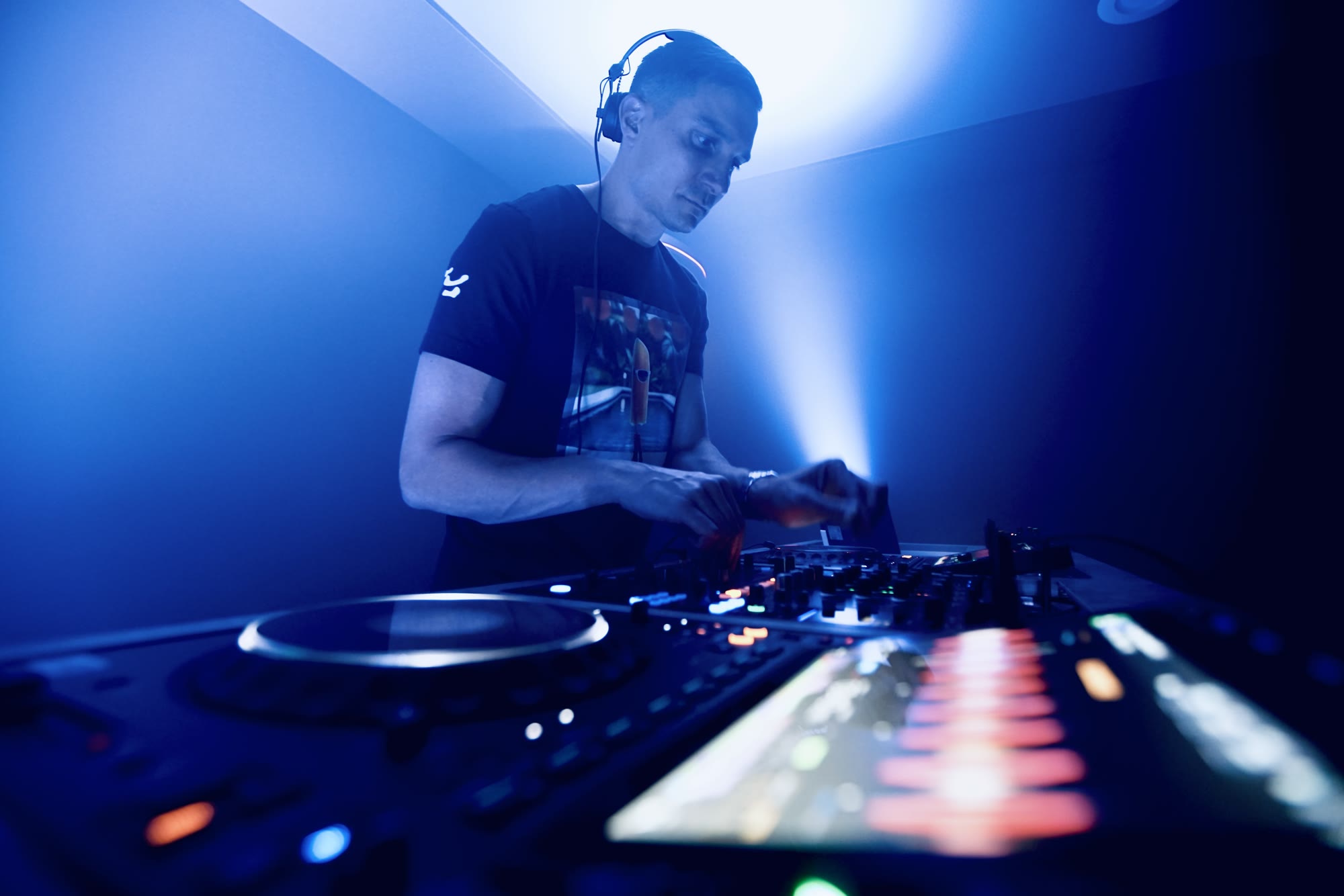 DJ Bolus performing behind the decks under blue lights