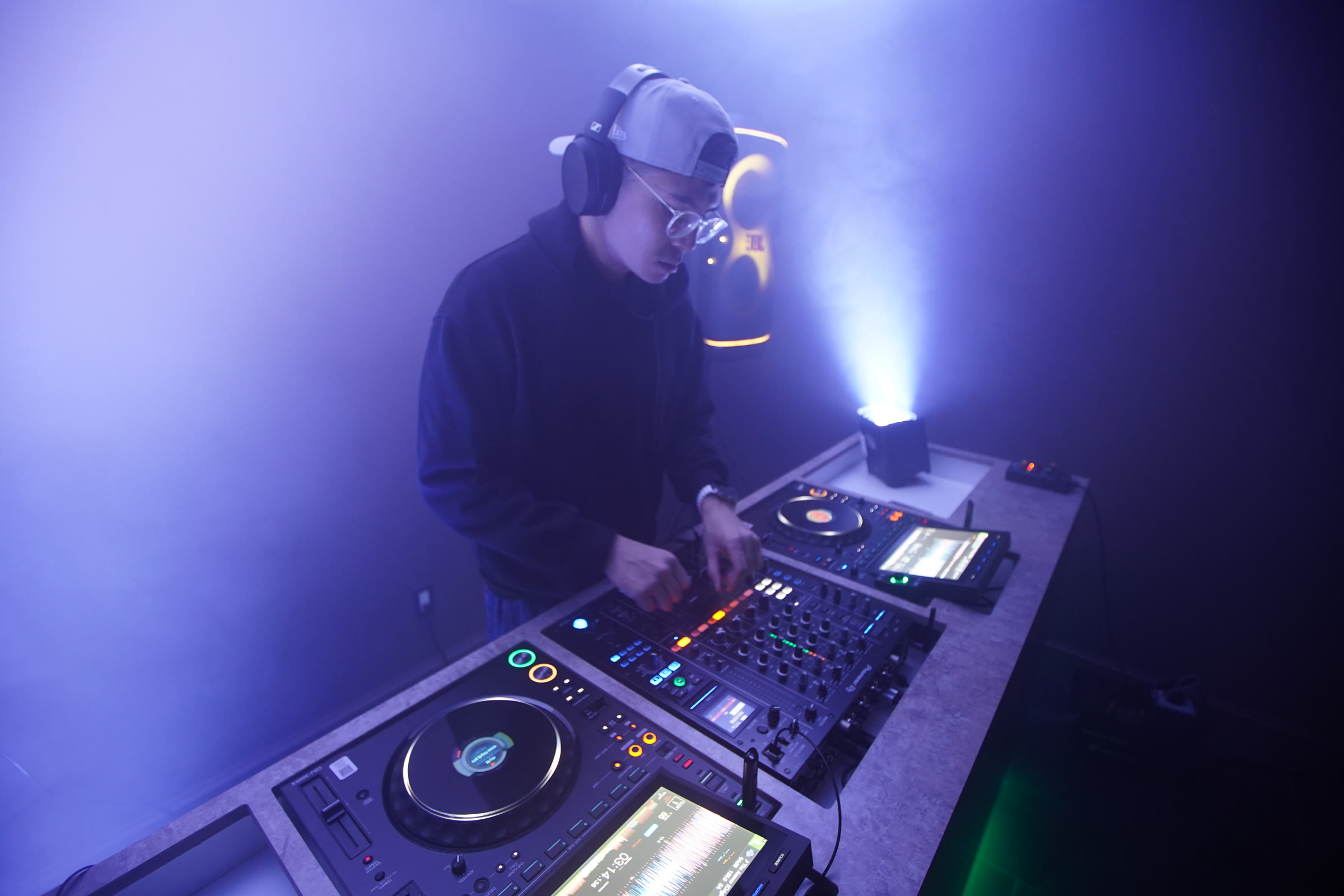 Pauly Cee performing a DJ set under blue and violet lights
